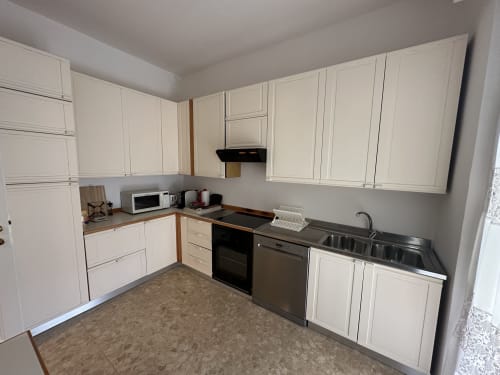 Cucina moderna nell'Appartamento Skyview del 10 Minutes B&B Verona con pensili color crema, elettrodomestici in acciaio inox e rivestimenti scuri
