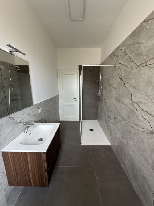 Bagno moderno nell'Appartamento Skyview di 10 Minutes B&B Verona, con rivestimenti effetto marmo, doccia walk-in e legno