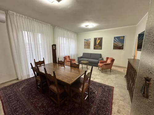 Ampio living con zona pranzo nell'Apartment Skyview del 10 Minutes B&B Verona, con tavolo in legno, sedute e divano grigio