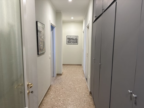 Moderno corridoio dell'appartamento Verona B&B con pareti bianche, pavimento in sughero e porte che conducono alle camere