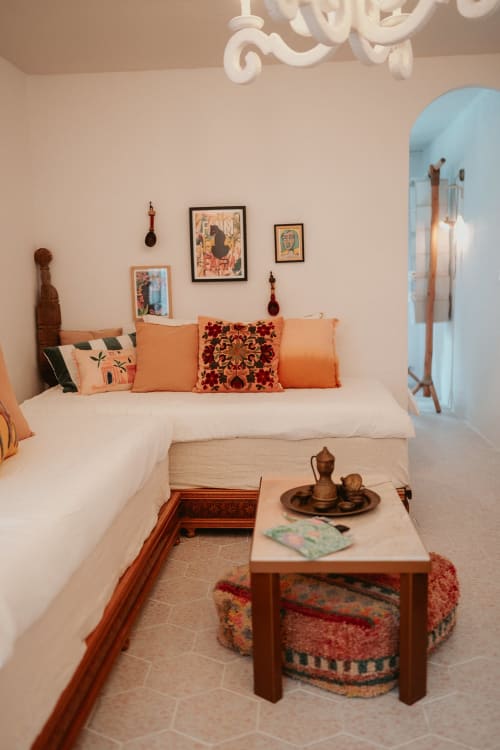 Chambre accueillante à la Bleu Guest House de Saint-François avec lit blanc, coussins orange, touches en terre cuite et décoration marocaine.