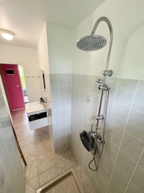 Douche moderne avec pomme de douche pluie aux Gîtes Bagatelle, Sainte-Rose. Salle de bains carrelée clair avec équipements épurés.