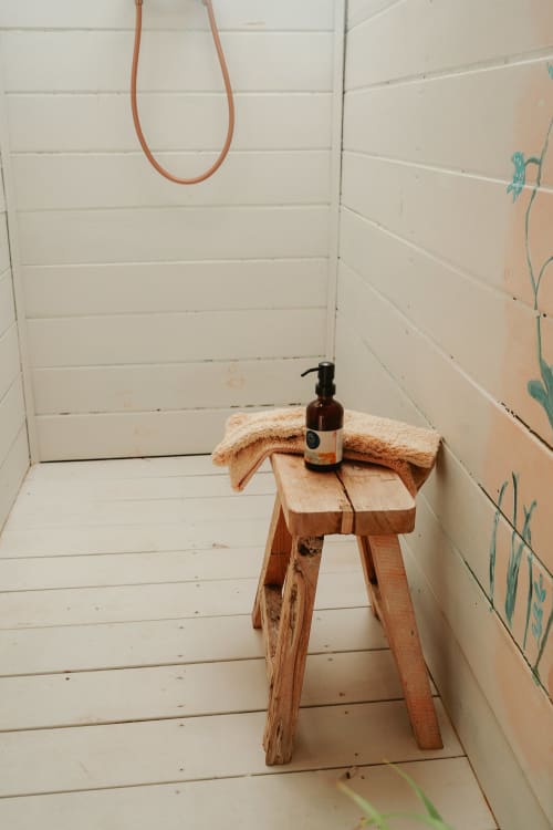 Petit tabouret en bois rustique avec serviette et distributeur de savon dans la salle de bain Suite Bleu Lavande de la Bleu Guest House, Saint-François