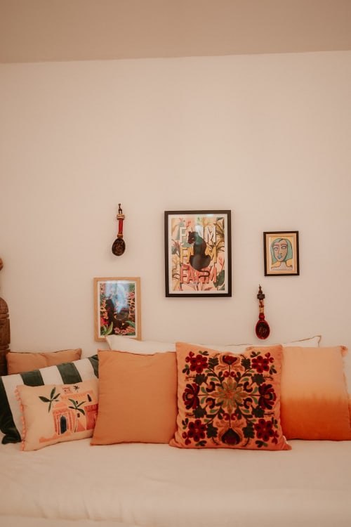 Suite Bleu du Gîte avec coussins orangés, œuvres d'art encadrées et éléments décoratifs muraux sur murs rose pâle