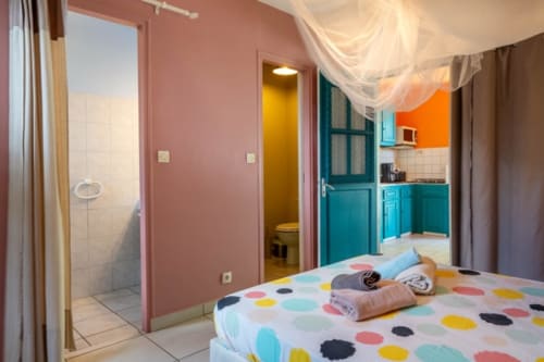Chambre d'hôtes colorée aux Gîtes Bagatelle : lit à pois, cuisine turquoise, murs roses et salle de bain privée