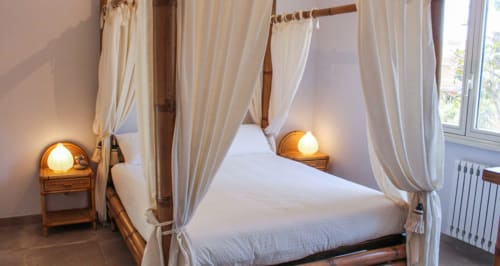 Elegante letto a quattro colonne con baldacchino e drappeggi color crema presso Maison Tizi a Fiumicino Roma