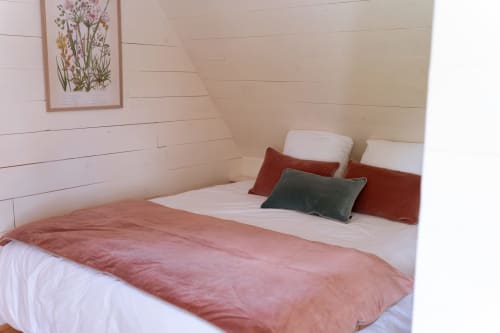 Chambre cosy de la villa Maisons Noisette à Saint-Pierre-des-Ormes avec murs en lambris blanc, parure rose et vue sur le jardin.