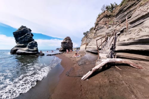 Scenic beach cove with dramatic rock formations and layered cliffs in Procida, Italy