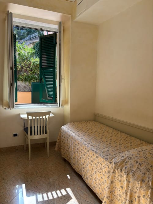 Chambre simple à l'Hôtel Feluca à Bonassola avec lit, bureau, chaise et fenêtre donnant sur le jardin