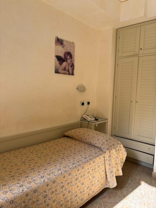 Chambre simple à l'Hôtel Feluca à Bonassola avec lit, armoire et décoration murale
