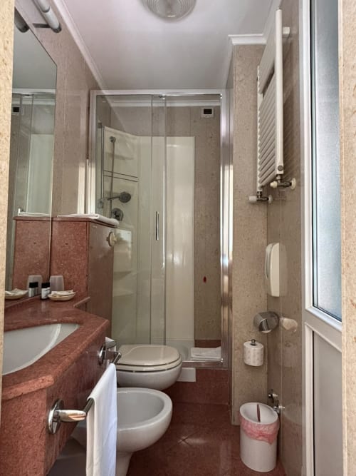 Salle de bain moderne à l'Hôtel Feluca à Bonassola avec vasque en marbre rouge, douche à l'italienne, bidet et sèche-serviettes électrique