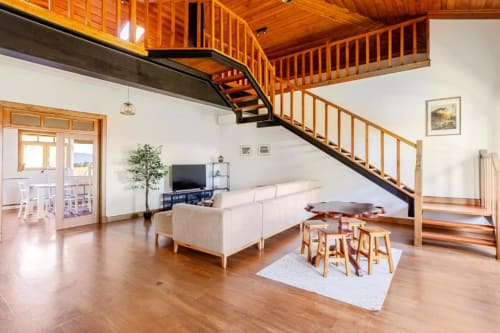 Modern 6-bedroom villa in Chaves with open-plan living, wooden staircase, cream sofa, and garden view