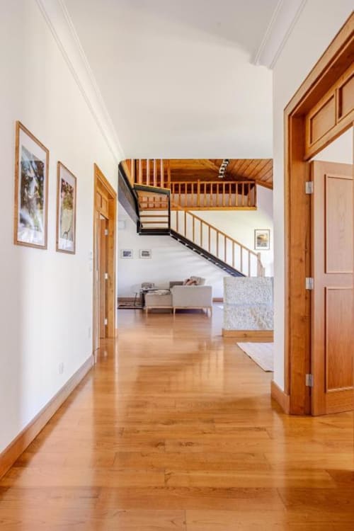 Spacious hallway in Chaves villa with wooden flooring, staircase, and open living area with furniture visible beyond