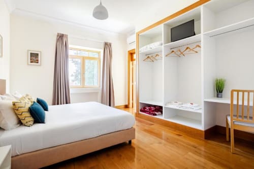 Modern bedroom with wooden floor, white built-in wardrobe, and garden view at Voluta villa in Chaves