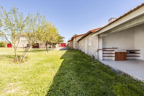 Spacious garden terrace of 6-bedroom villa in Chaves with green lawn, fruit trees, and covered outdoor dining area