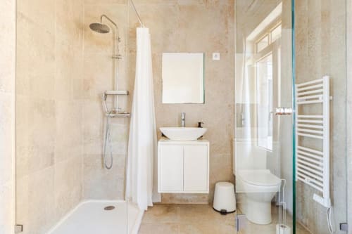 Modern bathroom in Chaves villa with shower, white vanity sink, toilet, and heated towel rack
