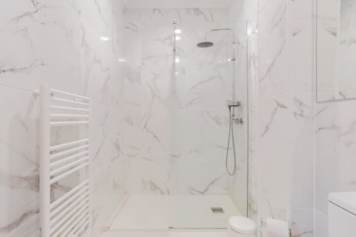 Modern marble bathroom with walk-in shower, white towel rack, and rainfall showerhead at Voluta villa in Chaves, Portugal