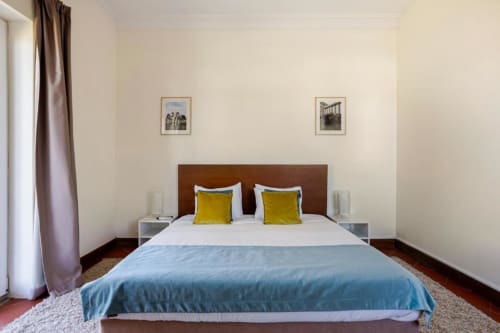 Spacious bedroom in Chaves villa with queen bed, yellow pillows, blue throw, brown headboard, and garden views