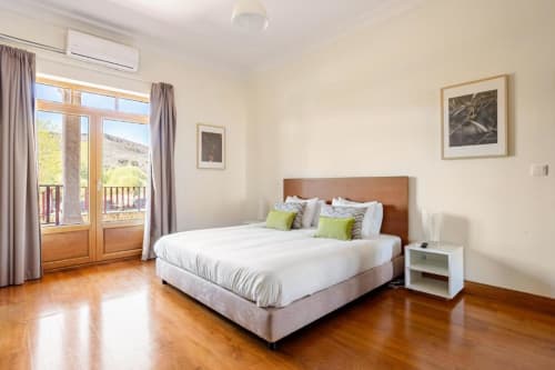Spacious bedroom in Chaves villa with king bed, wooden floors, balcony overlooking garden, and mountain views