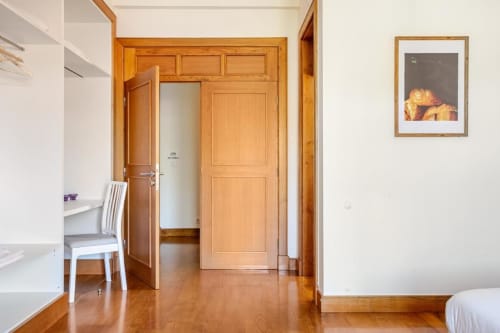 Modern B&B bedroom in Chaves with wooden doors, desk area, and polished wood flooring