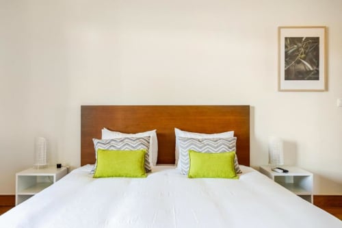 Bedroom with wooden headboard, white bedding, lime green pillows, and white nightstands in Chaves villa