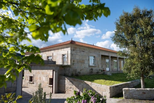 Modern stone villa with terrace and garden in Chaves, Portugal, featuring clay tile roof and lush grounds
