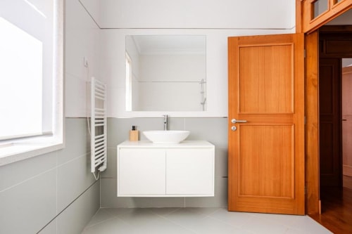 Modern bathroom with white vanity, round vessel sink, mirror, and wooden doors in Chaves villa