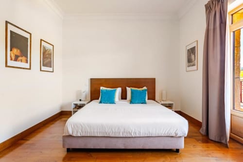Bright bedroom with wooden bed, white bedding, and turquoise pillows in Chaves villa