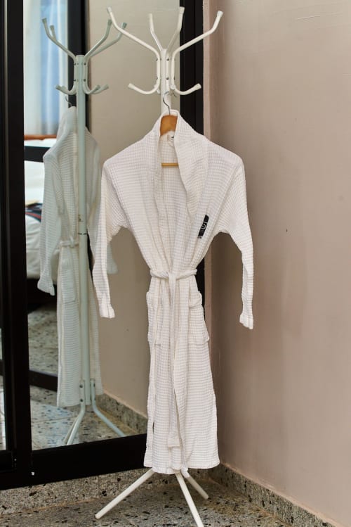 Robes blanches à tissage gaufré suspendues à un porte-manteau dans une chambre standard de l'Hôtel Yakro à Yamoussoukro