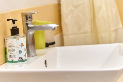 Lavabo de salle de bain à l'Hôtel Yakro à Yamoussoukro avec distributeur de savon et robinet chromé