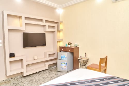 Chambre standard de l'Hôtel Yakro Yamoussoukro avec télévision, minibar et rangements intégrés modernes