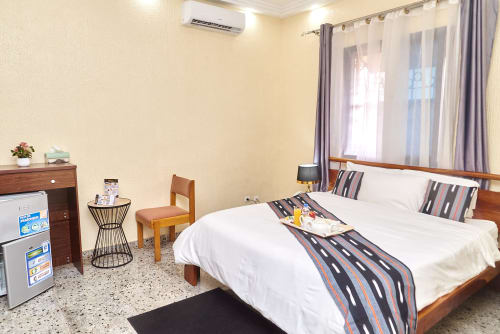 Chambre standard de l'Hôtel Yakro à Yamoussoukro : lit en bois, draps blancs, climatisation et équipements modernes