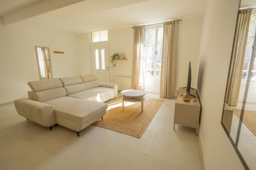 Salon lumineux du gîte Accolade Chez Ninon et Lou à Châteaudun avec canapé beige en L, table basse et vue sur la ville