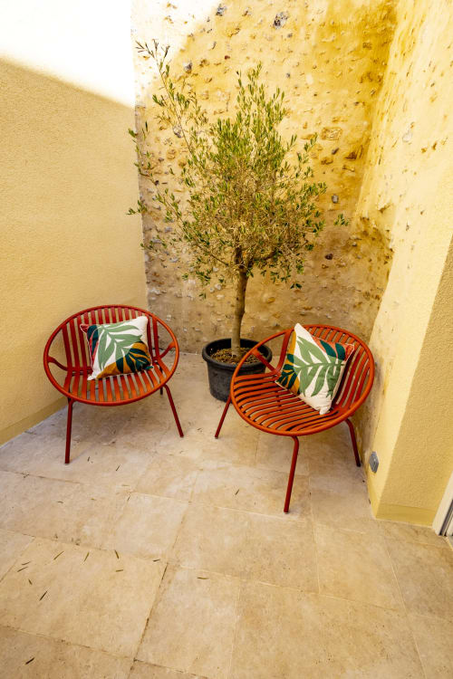 Coin lounge cosy du gîte Chez Ninon et Lou à Châteaudun avec chaises rouges et jardinière d'olivier