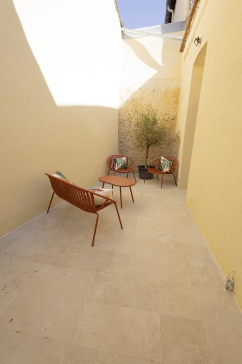 Terrasse ensoleillée du gîte Accolade Chez Ninon et Lou à Châteaudun avec chaises en terre cuite et olivier
