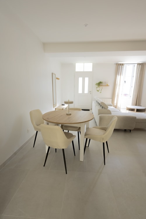 Salle à manger contemporaine du gîte Chez Ninon et Lou à Châteaudun avec table ronde en bois et chaises crème
