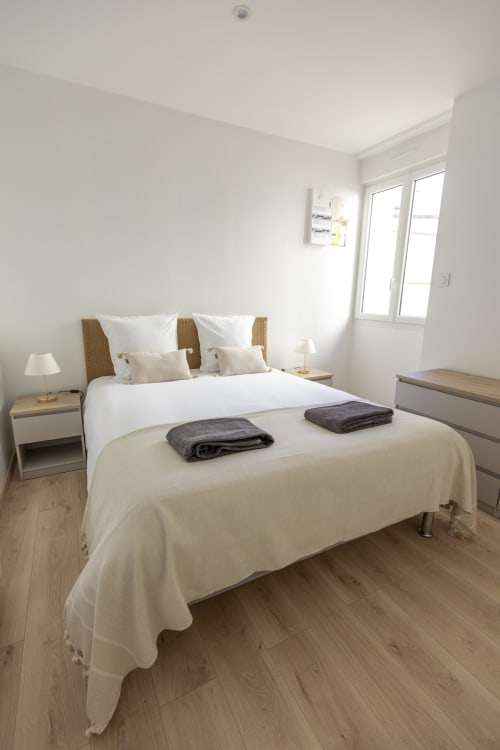 Chambre moderne à l'Accolade Châteaudun avec lit queen-size, tête de lit en rotin, parquet et vue sur la ville