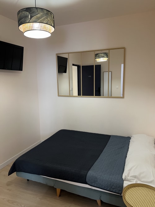 Chambre moderne de l'Hôtel Les Paquebots à Port-Vendres avec lit, miroir, suspension et TV murale