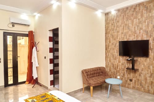 Suite moderne de l'Hôtel Yakro à Yamoussoukro avec TV écran plat, sièges confortables et décor contemporain