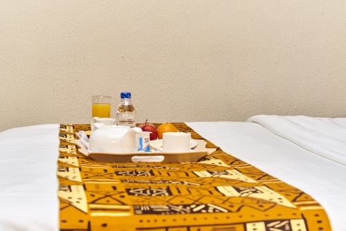 Suite d'hôtel avec lit, plateau de bienvenue, jus, eau, fruits et produits de toilette à l'Hôtel Yakro à Yamoussoukro