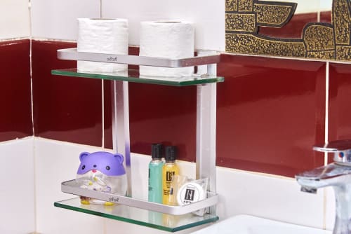 Étagère de salle de bains dans la suite Hôtel Yakro avec articles de toilette, serviettes et équipements à Yamoussoukro