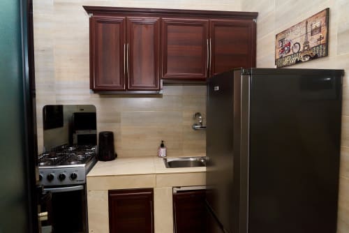 Suite de cuisine moderne à l'Hôtel Yakro à Yamoussoukro avec électroménagers en acier inoxydable et armoires en bois foncé