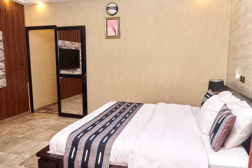 Suite moderne de l'Hôtel Yakro à Yamoussoukro avec lit queen, chemin rayé, placard miroir et vue sur la ville