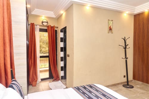 Chambre suite à l'Hôtel Yakro à Yamoussoukro avec balcon, mobilier moderne et accès à la terrasse vue sur la ville