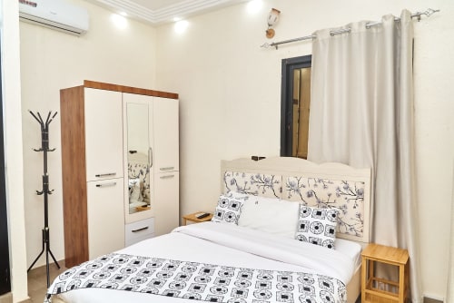 Chambre moderne à l'Hôtel Yakro à Yamoussoukro avec lit queen-size, armoire miroir et climatisation