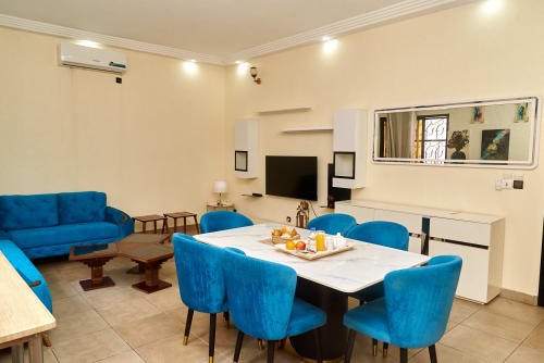 Appartement 3 chambres moderne à l'Hôtel Yakro à Yamoussoukro avec chaises de salle à manger bleues, TV écran plat et design contemporain