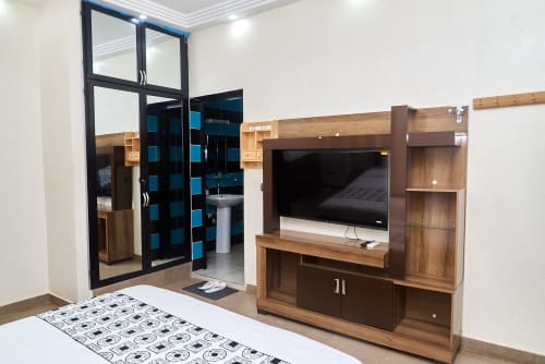 Appartement 3 pièces moderne à l'Hôtel Yakro à Yamoussoukro avec mobilier de chambre en bois, TV écran plat et salle de bain privée