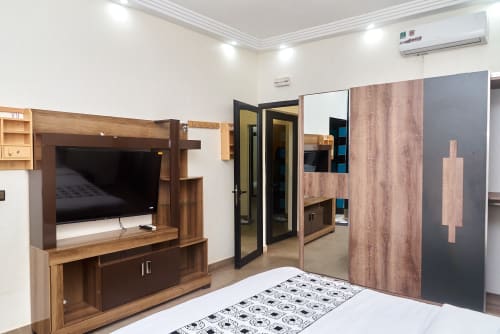 Appartement 3 chambres moderne à l'Hôtel Yakro à Yamoussoukro, avec mobilier en bois, télévision écran plat et climatisation.