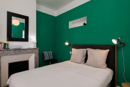 Chambre moderne de la maison d'hôtes Les Petits Toits aux murs vert émeraude, plafond blanc, lit avec oreillers beige et cadre noir