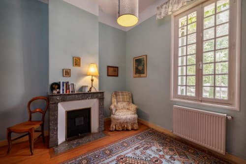 Intérieur élégant du cottage Les Petits Toits à Galgon avec cheminée, fauteuil et mobilier d'époque